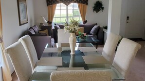 A living room with a glass coffee table, beige patterned sofas, and a white vase with flowers. - 5 Bed Florida Villa (Davenport)