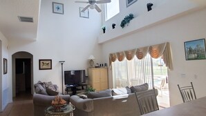 A spacious living room with a sofa set, a television, and a dining table. - 5 Bed Florida Villa (Davenport)