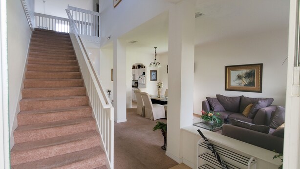 A staircase leading to a second floor, a dining area with a table and chairs, and a living room with a sofa and a framed picture on the wall. - 5 Bed Florida Villa (Davenport)