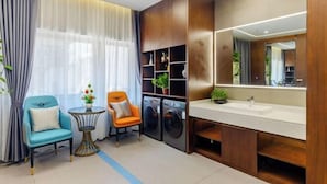 Une salle de bain moderne avec un grand miroir, des meubles en bois, un lavabo et un lave-linge.