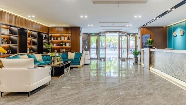 Un hall d’hôtel comprenant un comptoir d’accueil, un espace salon et une porte tournante.