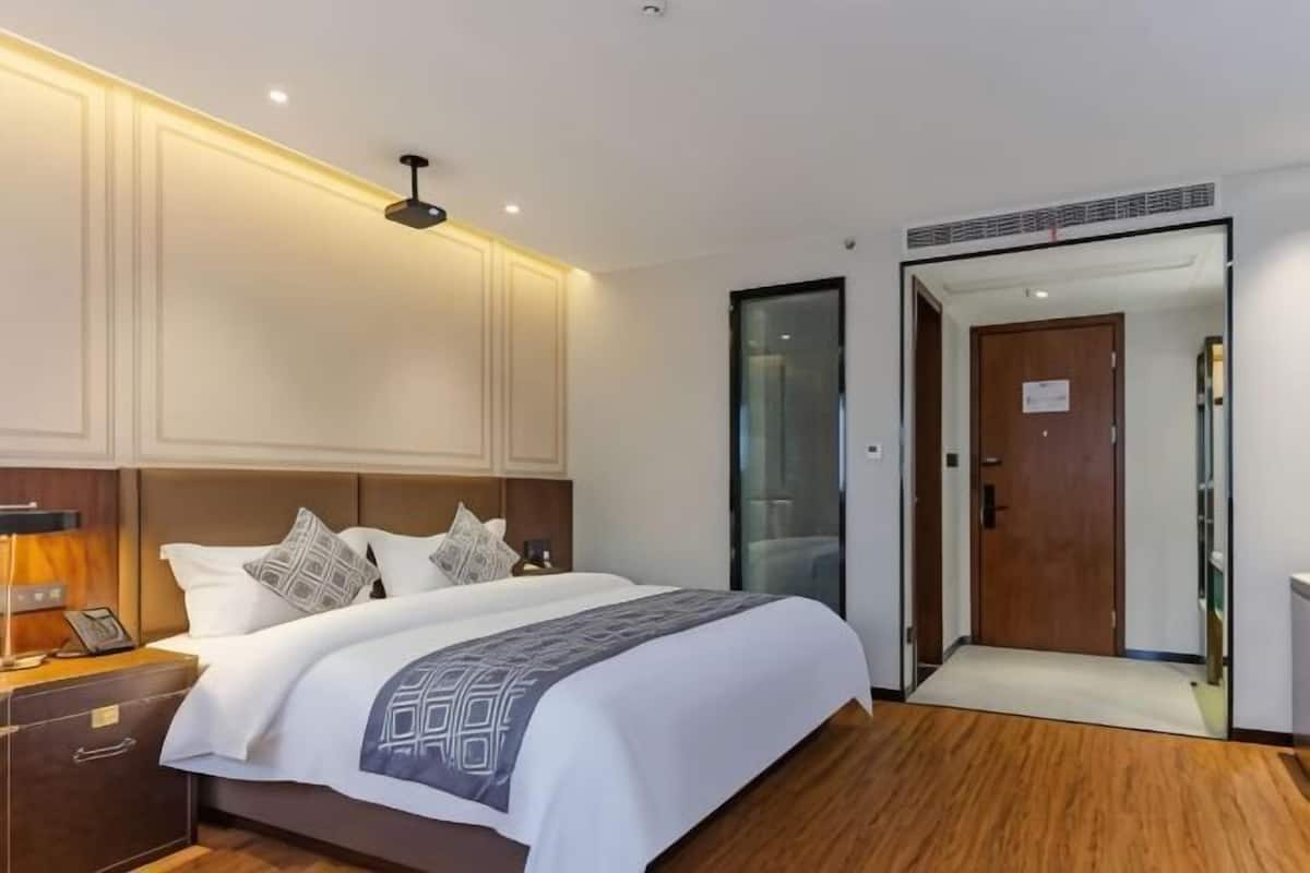 Une chambre dâhĂŽtel moderne avec un grand lit, des tables de chevet, une petite table, un bureau et une armoire.