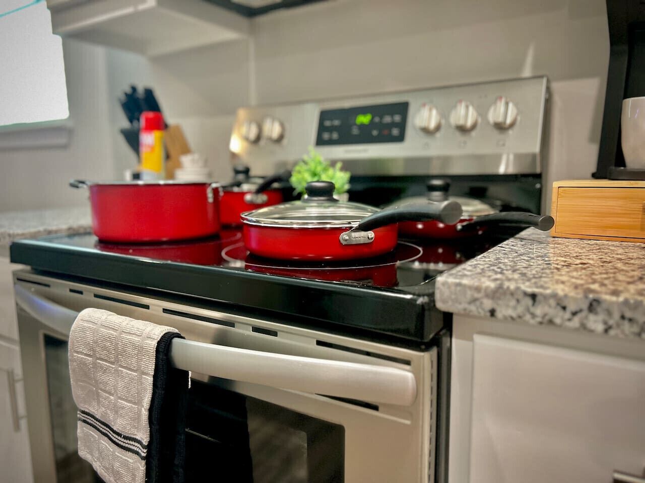 A kitchen with a stove, pots, and a digital clock.