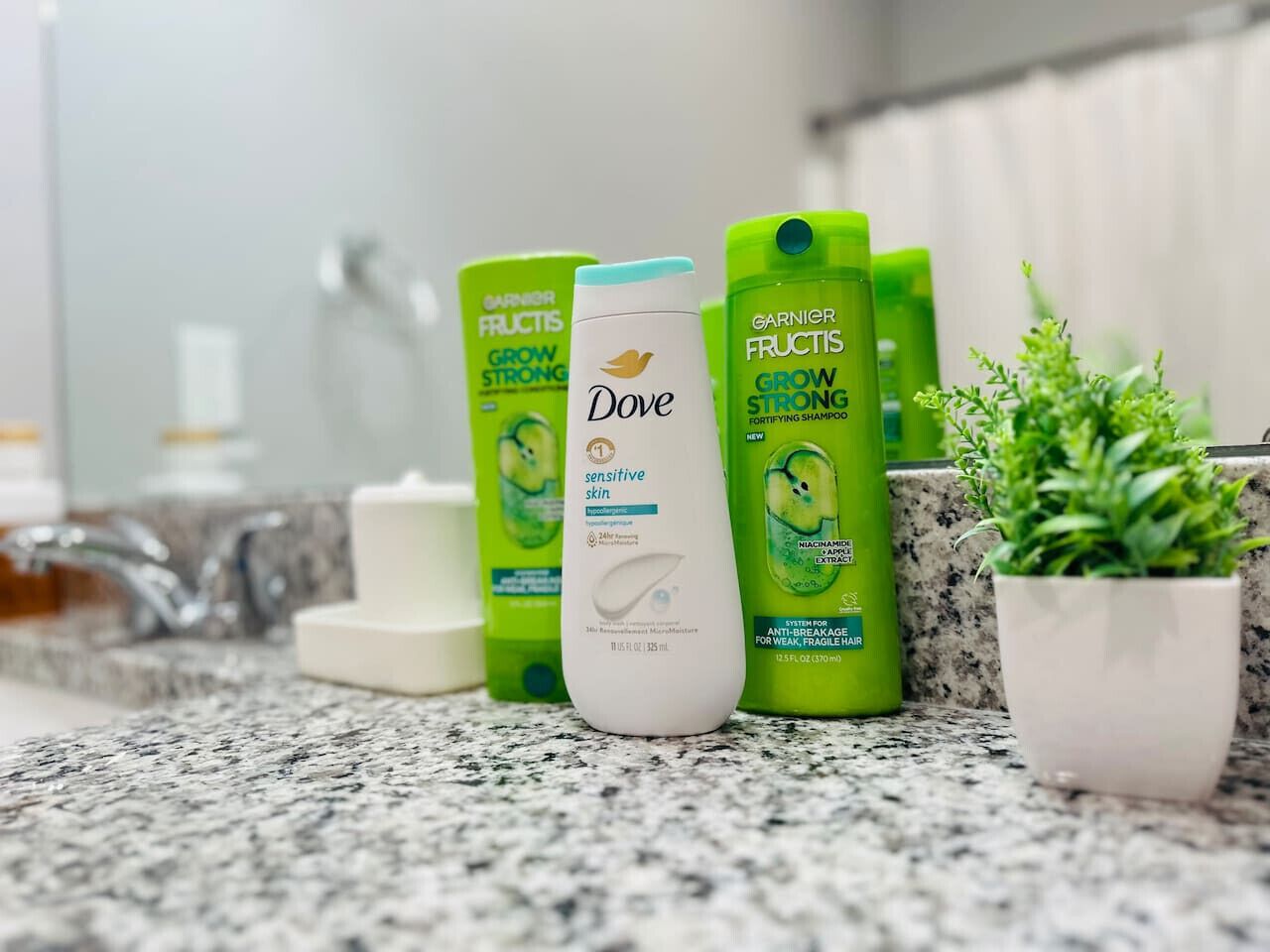 Un ripiano del bagno con diversi prodotti per la cura dei capelli, tra cui shampoo Garnier Fructis e Dove.