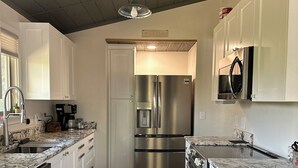 A modern kitchen with white cabinets, stainless steel appliances, and a wooden floor. - Charming 2-bedroom cottage waterfront on the little Deschutes River  La Pine, OR (La Pine)