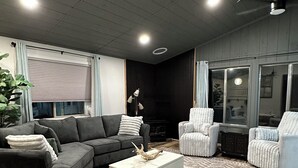 A modern living room with a sectional sofa, a white coffee table, and two armchairs. - Charming 2-bedroom cottage waterfront on the little Deschutes River  La Pine, OR (La Pine)