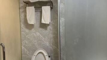 Casa de banho com sanita, um porta-toalhas com duas toalhas e uma parede de mármore.