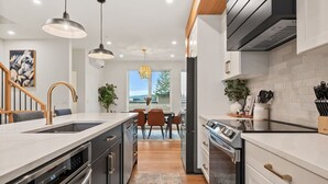 A modern kitchen with a central island, built-in oven, and stainless steel appliances.