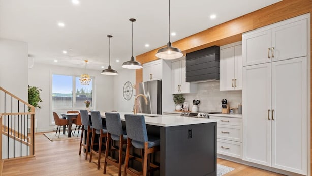 A modern kitchen with a central island, pendant lighting, and white cabinetry.