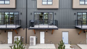 A modern apartment building with multiple balconies, large windows, and a flat roof.