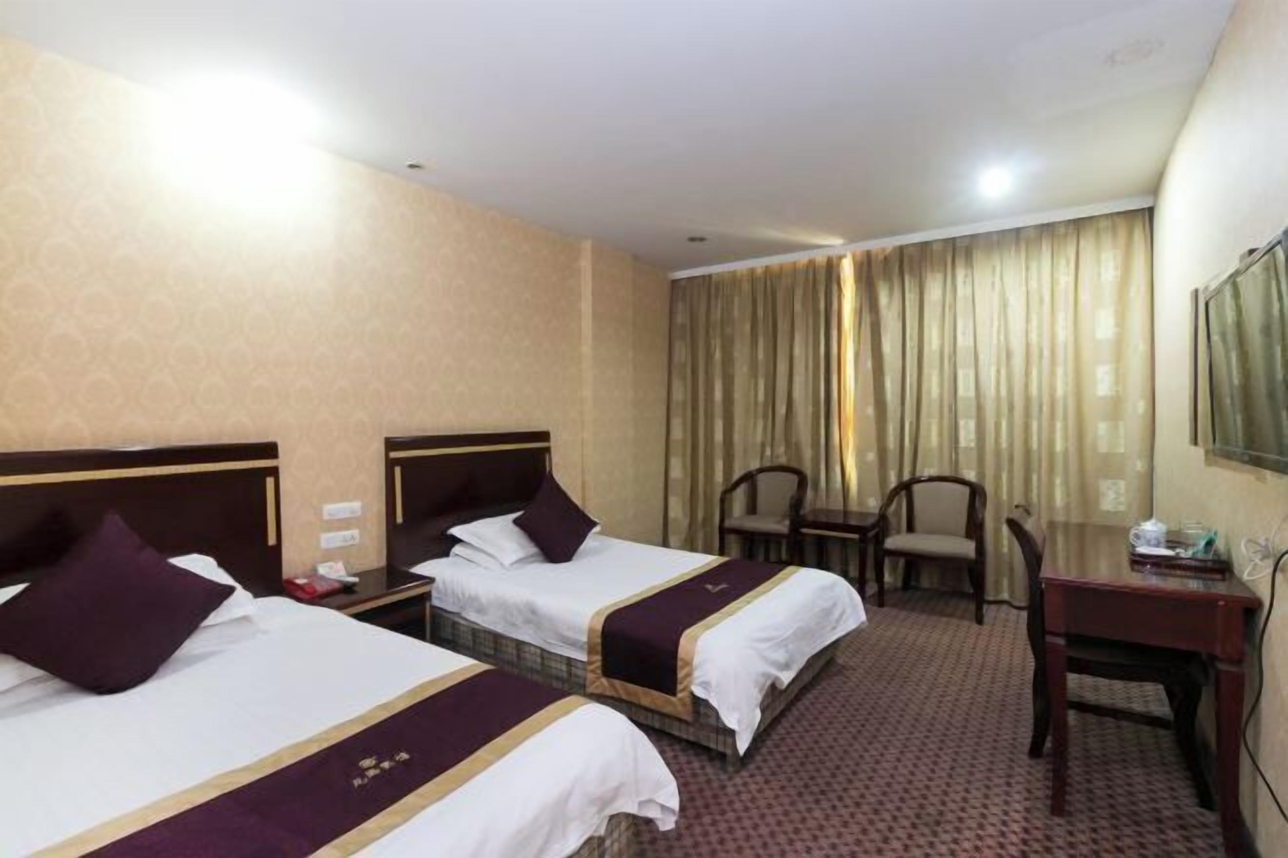 Une chambre d’hôtel avec deux lits, un bureau, une chaise et un téléviseur.