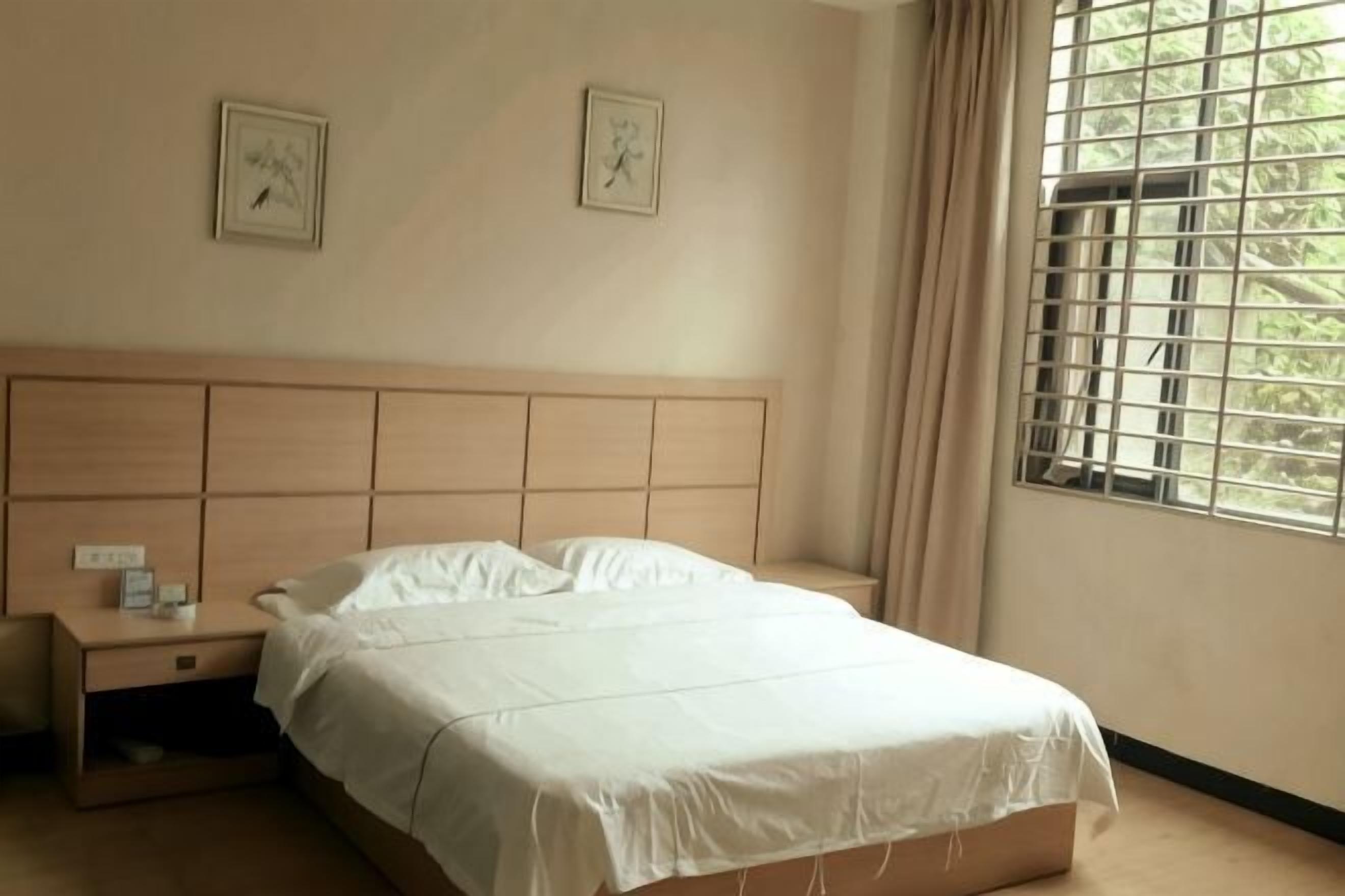 A bedroom with a bed, nightstand, and window with curtains.