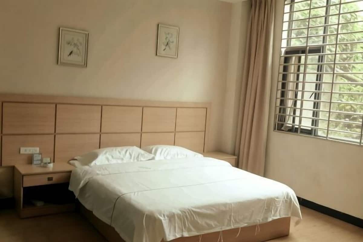 A bedroom with a bed, nightstand, and window with curtains.