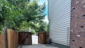A concrete driveway leading to a gated entrance, surrounded by a wooden fence and a brick wall. - Convenient Walkout Basement Apartment, private entrance in Aurora with WiFi (Aurora)