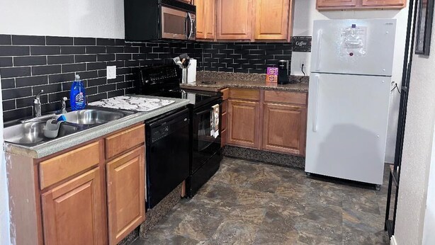 A kitchen with wooden cabinets, a black microwave, a white refrigerator, and a granite countertop. - Convenient Walkout Basement Apartment, private entrance in Aurora with WiFi (Aurora)