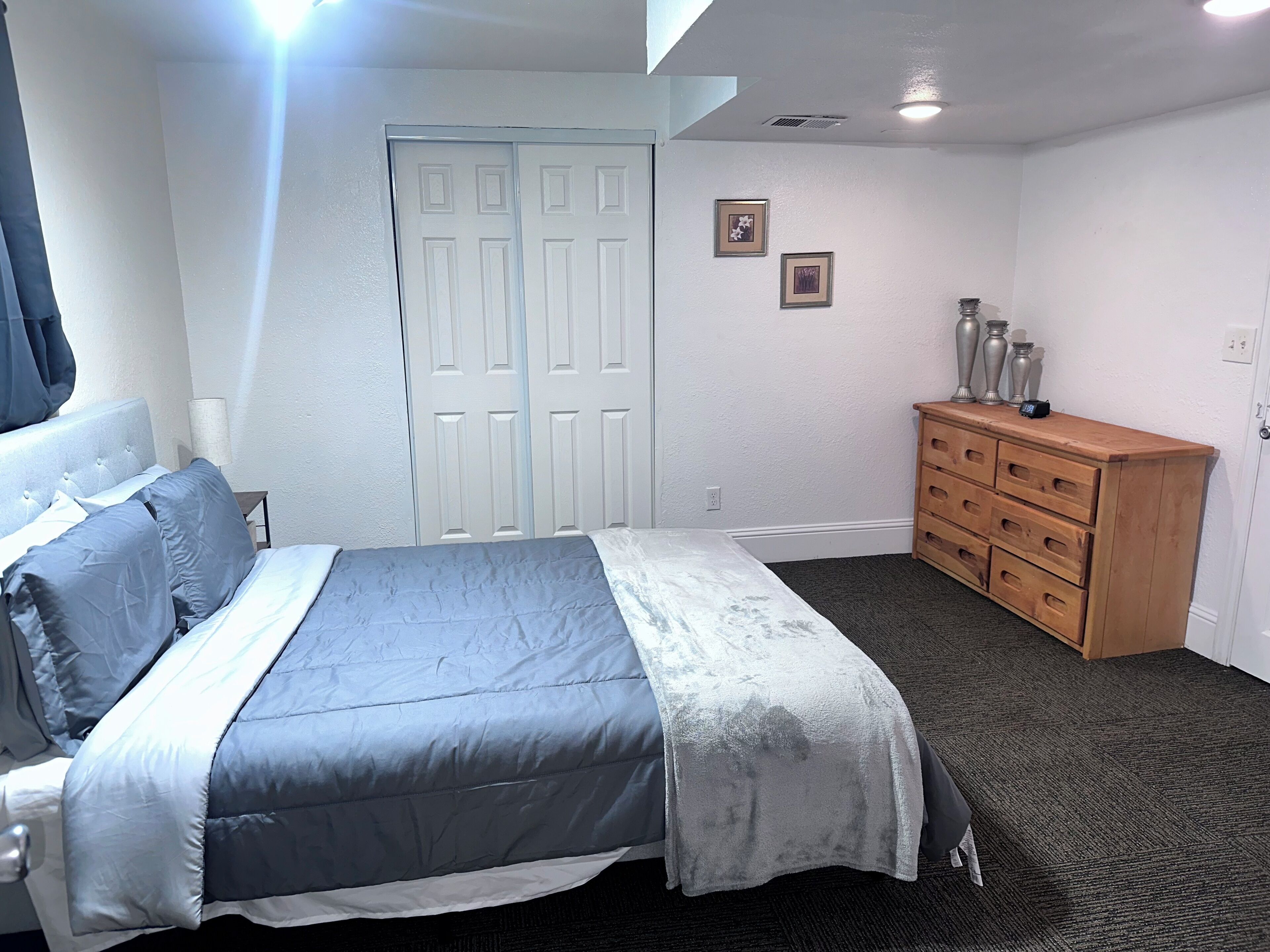 A bedroom with a bed, a dresser, and a door.