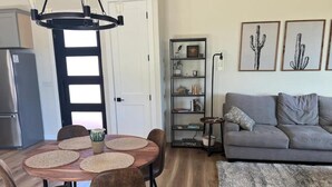 Un salon moderne avec un canapé gris, une table à manger agrémentée de sets de table en fibres tressées et une bibliothèque.