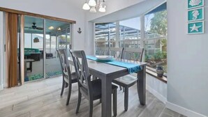 Een eetruimte met een tafel, stoelen en uitzicht door grote ramen.
