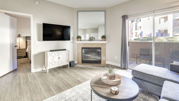 A modern living room with a fireplace, a flat-screen TV, and a balcony with outdoor furniture. - Sunny San Diego Condo w/ Pool Access Near Wineries (San Diego)