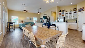 A spacious kitchen with a wooden dining table, wicker chairs, and a ceiling fan. - Pet Friendly, Golf Cart Included, Walk to the Beach (Port Aransas)