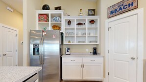 A kitchen with white cabinetry, a stainless steel refrigerator, and a sign above the cabinets that reads "Jones-N-Dine The Beach Port Aransas." - Pet Friendly, Golf Cart Included, Walk to the Beach (Port Aransas)
