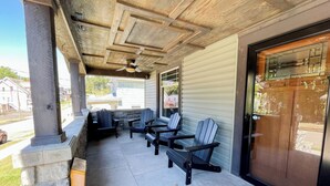 A covered patio area with stone columns, a ceiling fan, and Adirondack chairs.