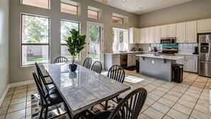 Una cocina amplia con una isla central, ventanas grandes y un ventilador de techo.