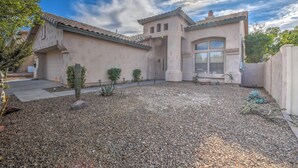 Una casa con un patio, un cactus y un cielo despejado.