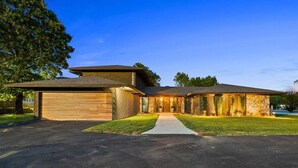 Una casa moderna de dos pisos con garaje, un porche cubierto y un césped bien cuidado.