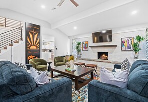 A modern living room with a fireplace, seating, and a staircase. - Game Room | Karaoke | Lakefront | Sleeps 15 (Hot Springs)