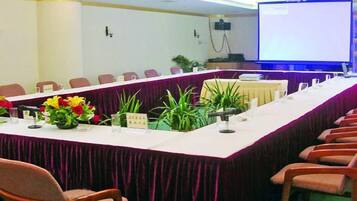 A conference room with a long table, chairs, and a projector screen.