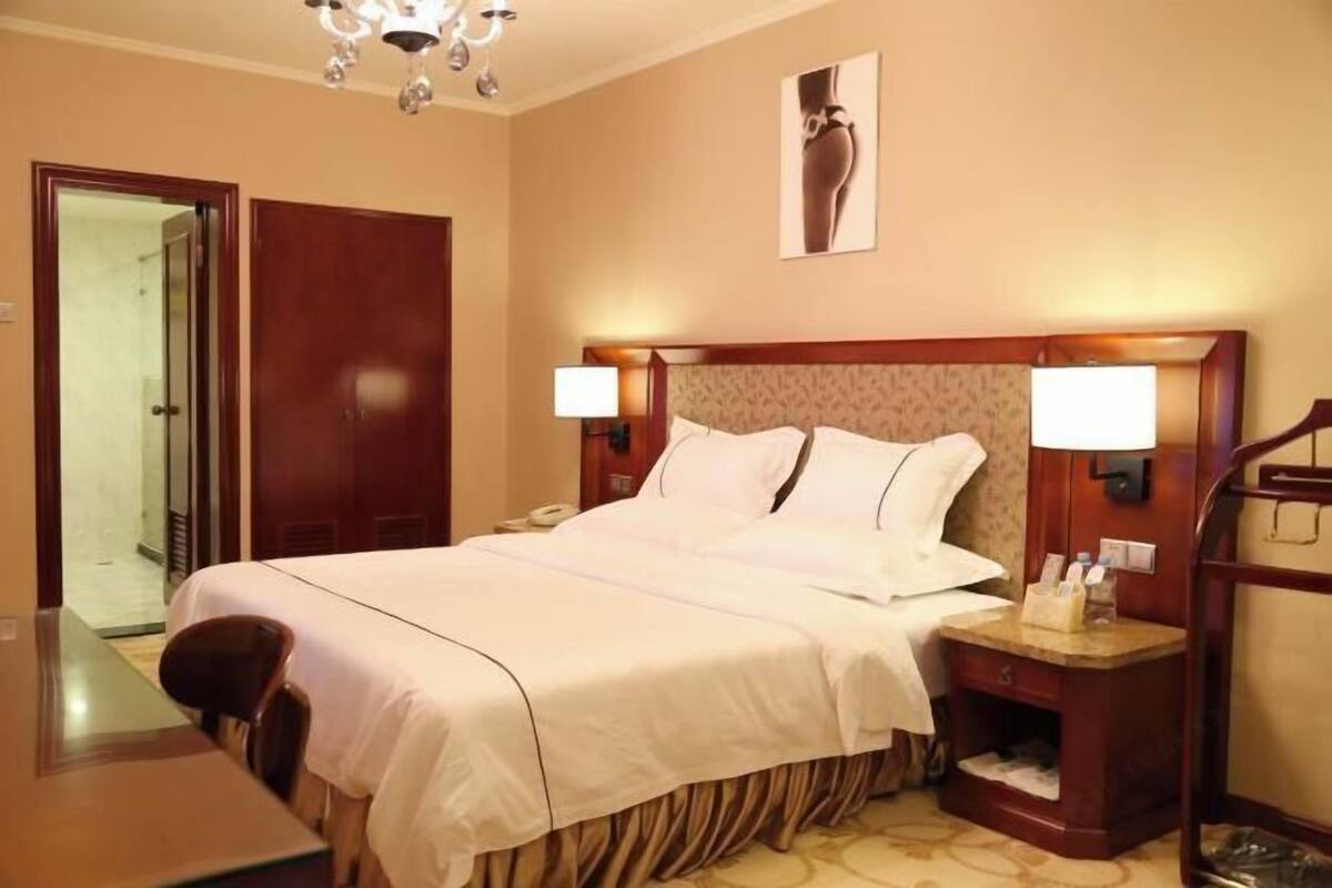 A hotel room with a bed, bedside tables, a desk, and a chair.