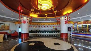 A lobby with a large black and white yin-yang symbol on the floor, red lanterns, and a modern chandelier.