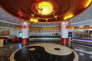 A lobby with a large black and white yin-yang symbol on the floor, red lanterns, and a modern chandelier. - Zhongyu Hotel (Beihai)
