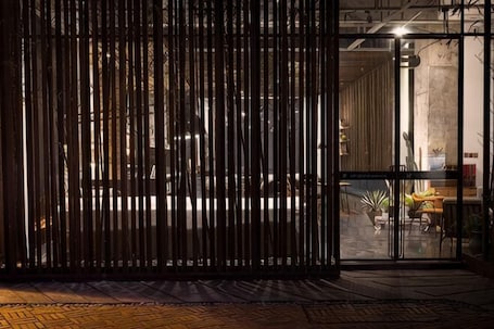 A room with a glass door, a wooden partition, and a visible interior with a sofa and potted plants.. Yiju Design Hotel