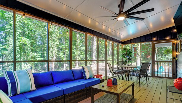 A covered outdoor seating area with a blue sofa, a wooden table, and a ceiling fan. - Waterfront Retreat on a Lake Lanier Cove w/ Dock (Dawsonville)
