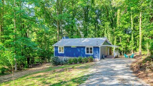 A small blue cabin with a gravel driveway, surrounded by dense forest. - Waterfront Retreat on a Lake Lanier Cove w/ Dock (Dawsonville)