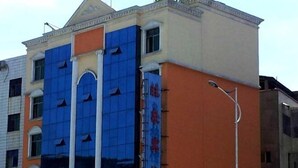 Un edifici de diversos pisos amb façana blava i un rètol amb lletra vermella.