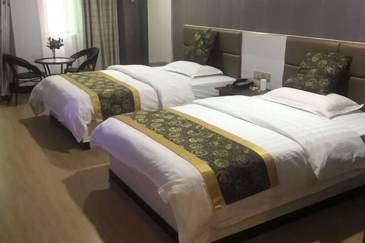 Une chambre d’hôtel avec deux lits, une petite table avec des chaises et une table de chevet avec un téléphone.