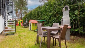 A patio area with a table and chairs, a children's play structure, and a stone sculpture. - Apartment in Jaroslawiec Near the Beach (Postomino)