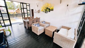 A cozy room with wicker furniture, a dining table, and a view of the outside. - Apartment in Jaroslawiec Near the Beach (Postomino)