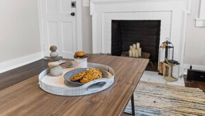 A wooden dining table with a tray of cookies and a stack of stones. - Downtown - Sleeps 8 - We Love Doggies! (Wilmington)