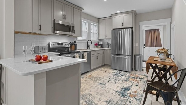 A modern kitchen with stainless steel appliances, a marble countertop, and a dining area with a wooden table and chairs. - Downtown - Sleeps 8 - We Love Doggies! (Wilmington)
