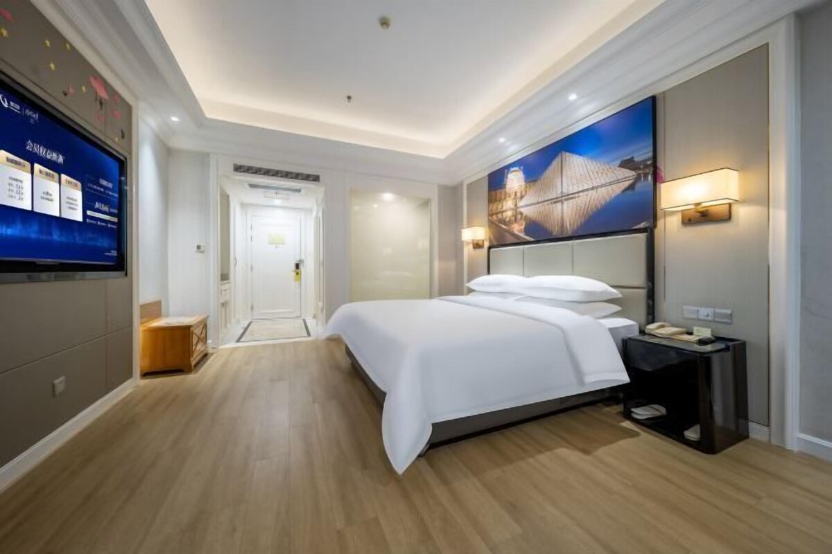 Une chambre d’hôtel avec un lit, une télévision, un téléphone fixé au mur et un tableau.