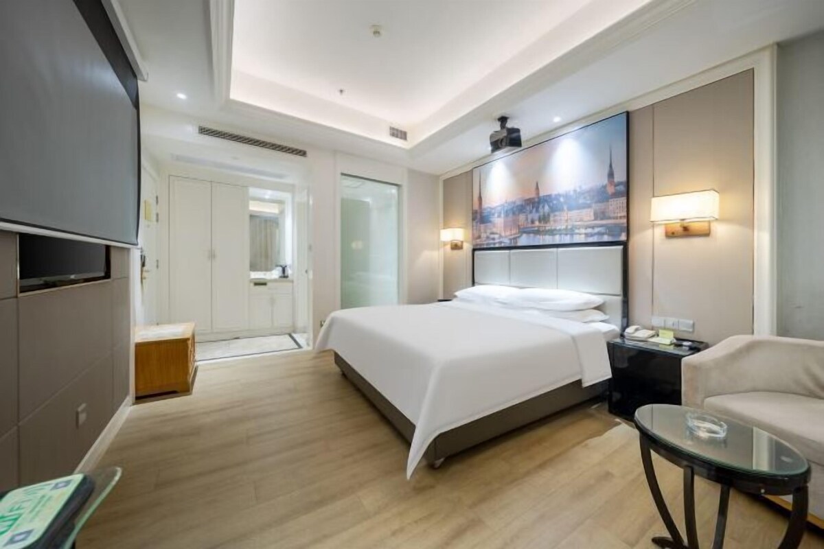Une chambre d’hôtel équipée d’un lit, d’une table de chevet, d’une chaise et d’un téléviseur.