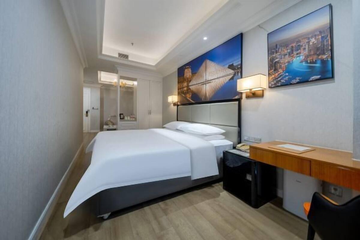 Une chambre d’hôtel moderne, équipée d’un lit, d’un bureau et de deux tableaux accrochés au mur.