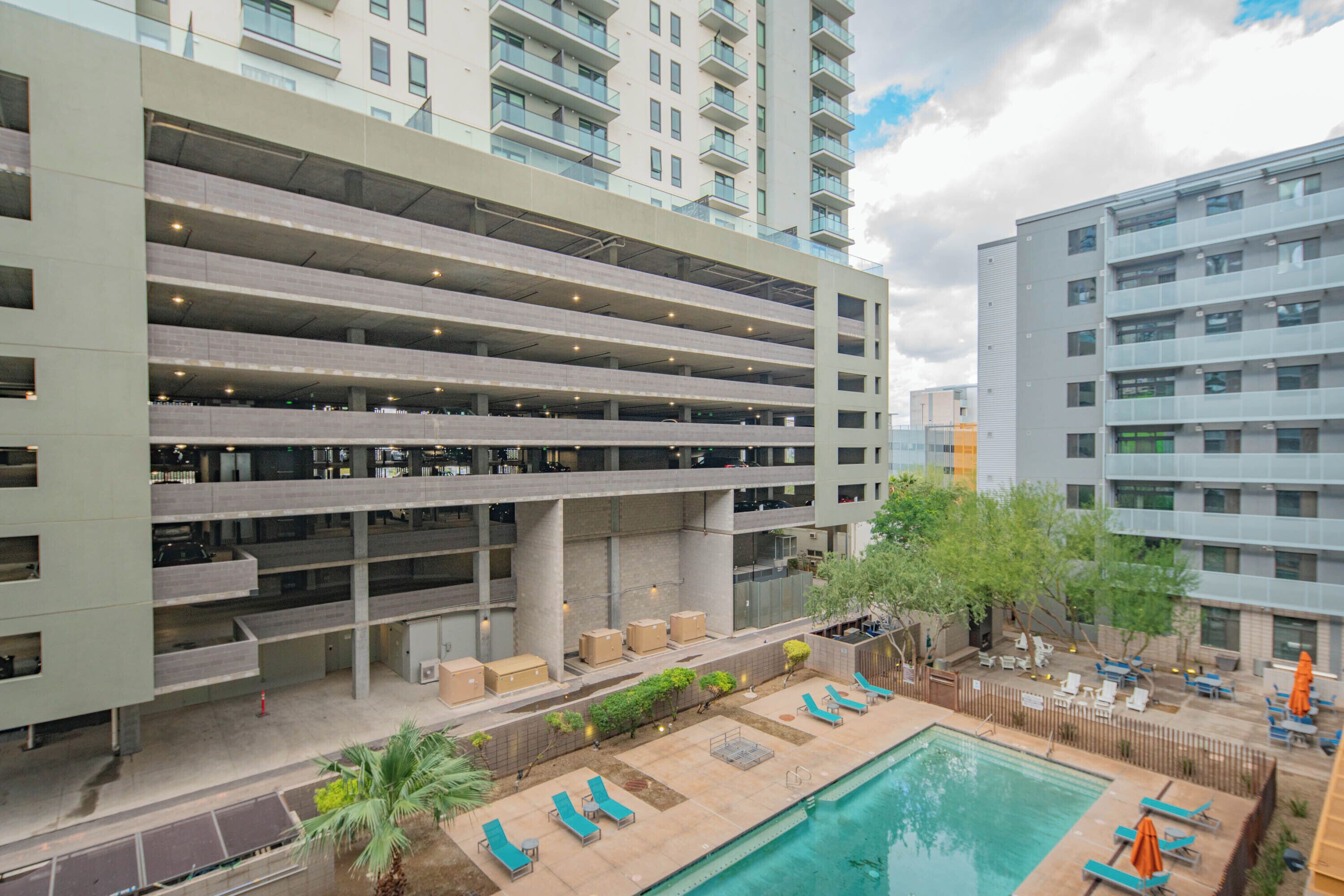 A multi-story parking garage with a rooftop pool area featuring lounge chairs and umbrellas.