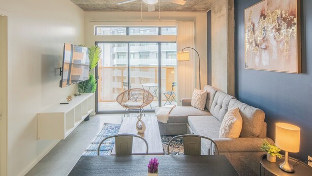 Ein modernes Wohnzimmer mit einer Couch, einem Esstisch und einem Deckenventilator.