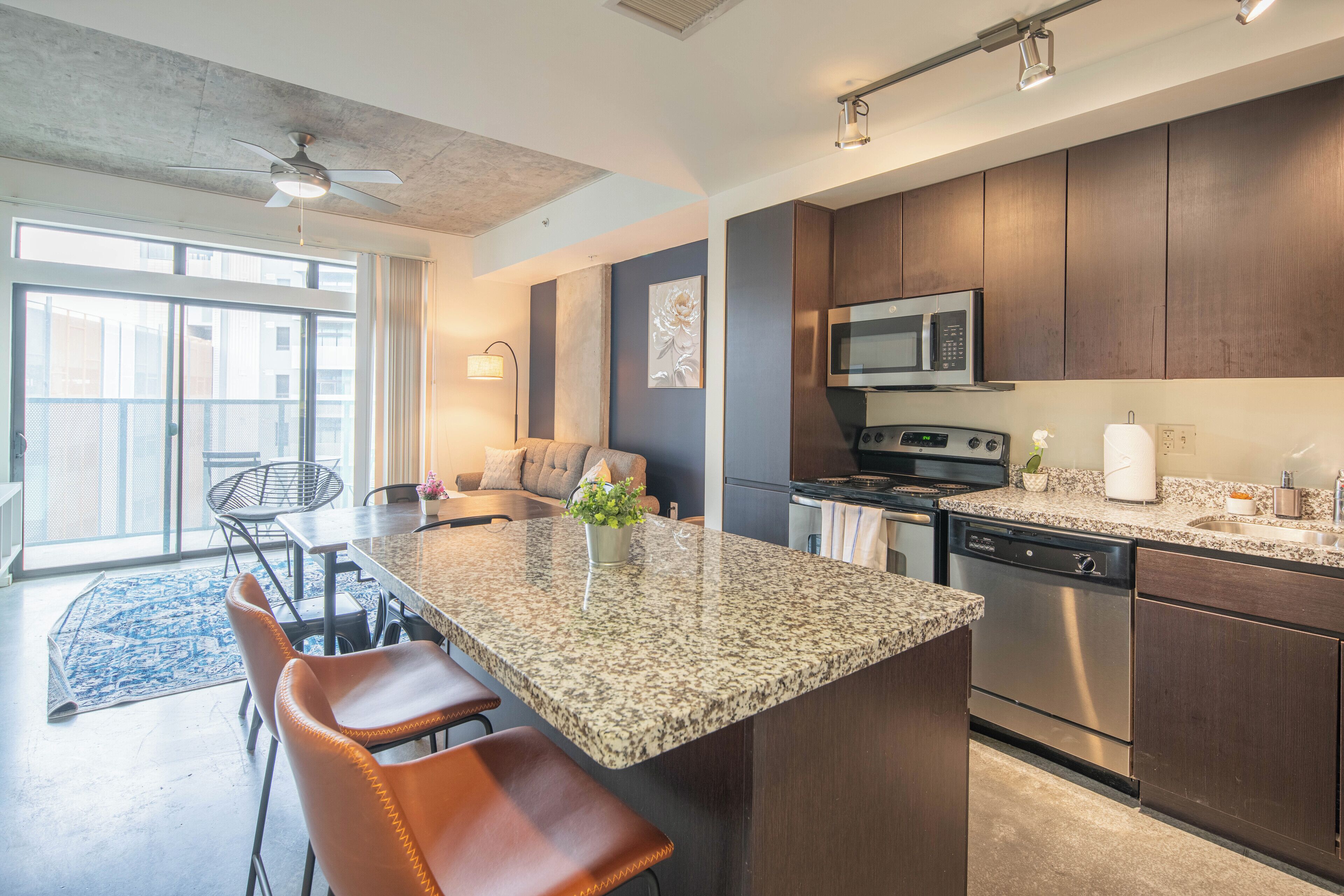 Una cocina moderna con encimeras de granito, electrodomésticos de acero inoxidable y una isla grande con taburetes de bar.