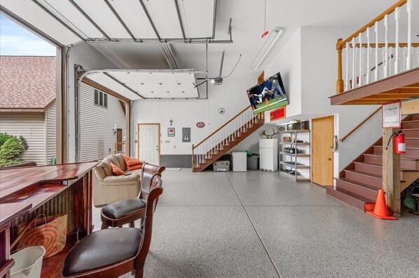Un amplio espacio habitable con una larga mesa de madera, un sofá y una escalera que conduce a un nivel superior.